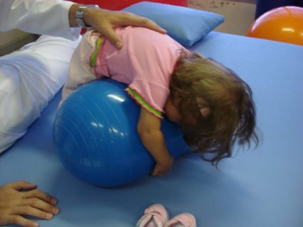 Во время занятия можно, положив ребёнка на гимнастический шар